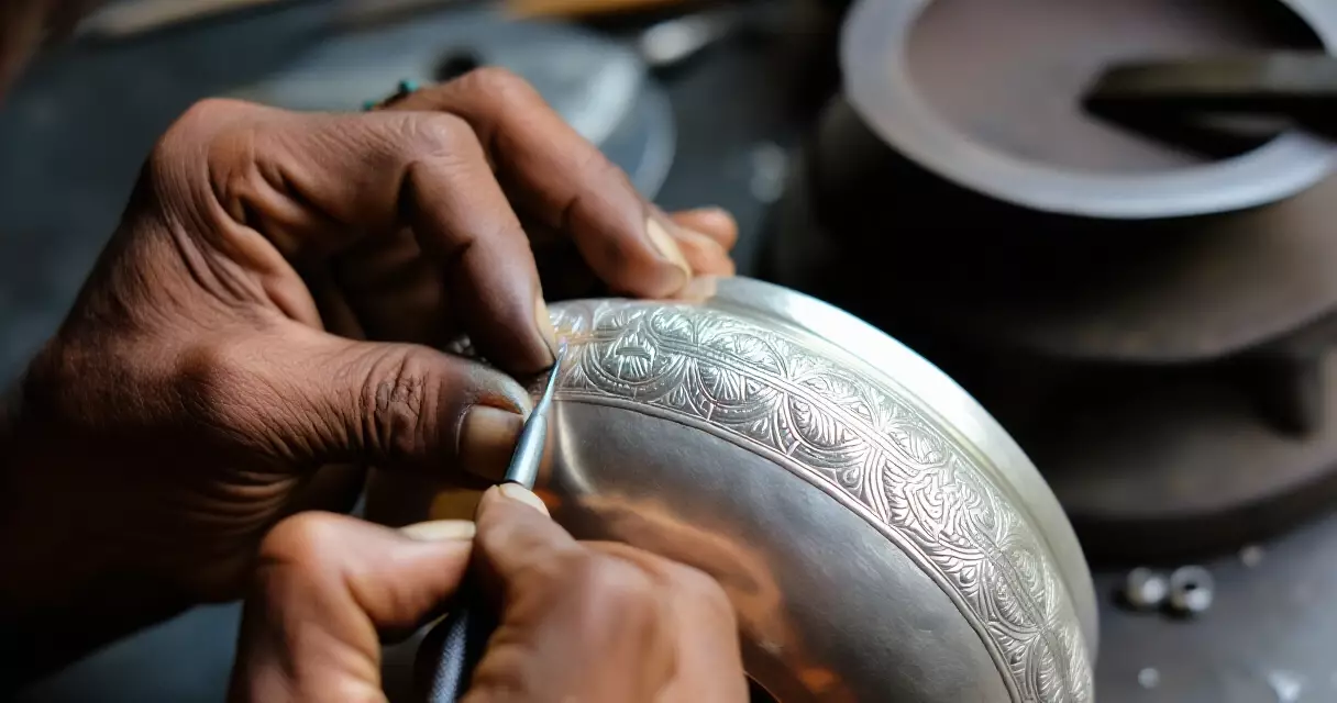 မြန်မာ ငွေထည်သမားသည် ငွေဗူးပေါ် ရိုးရာပန်းပွင့်ပုံ ထွင်းဆွဲနေသည်