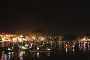 Vibrant night scene showcasing bustling riverside festivities in Hoi An Ancient Town, Vietnam.