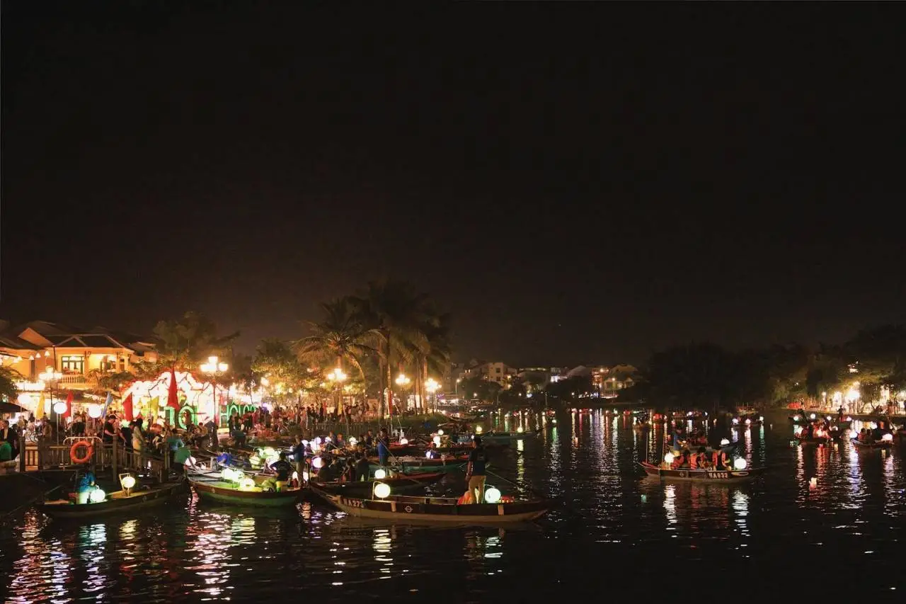 Vibrant night scene showcasing bustling riverside festivities in Hoi An Ancient Town, Vietnam.