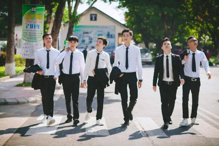 Group of young men in formal attire walking on a pedestrian lane in Hue, Vietnam.