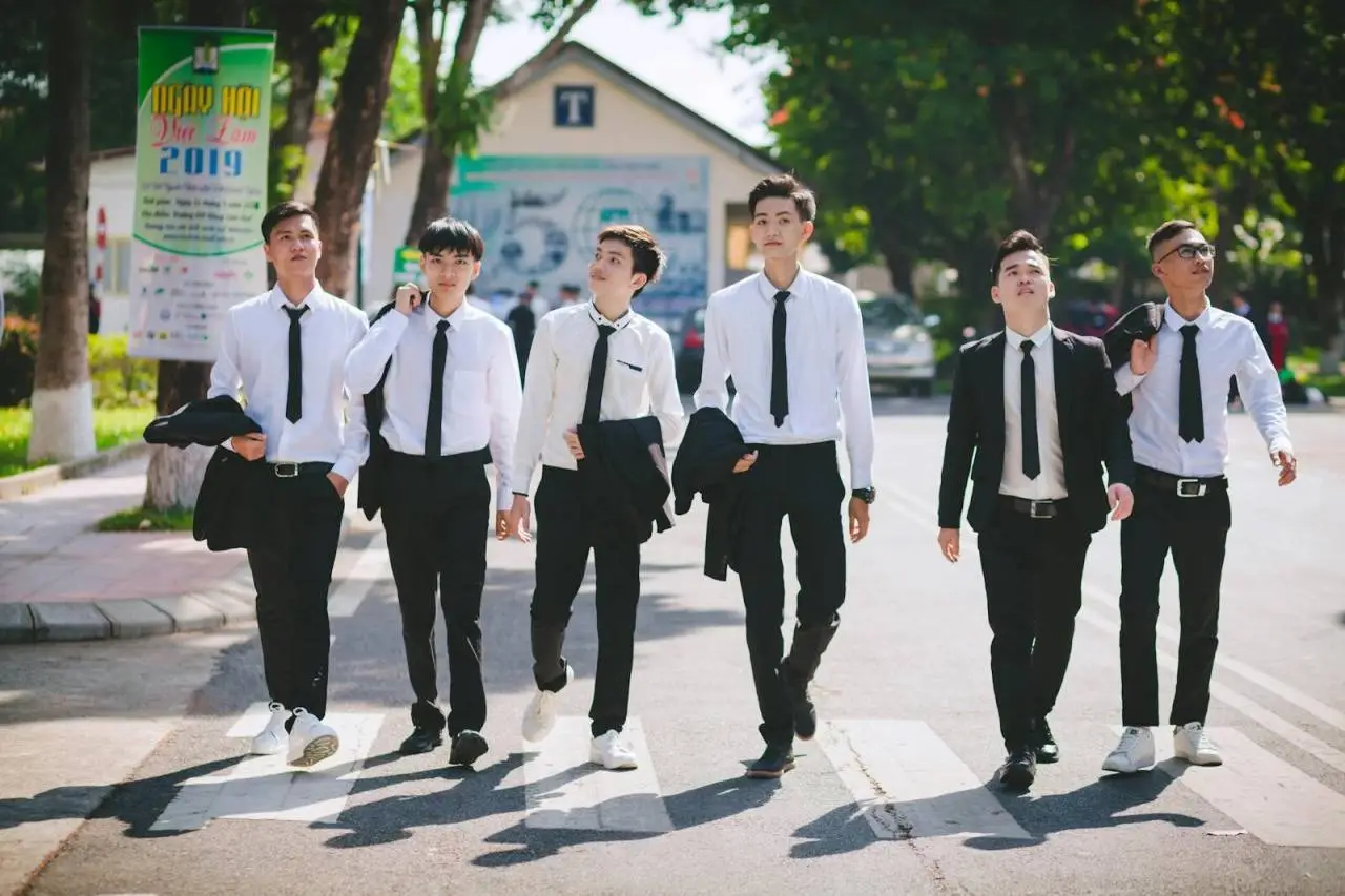 Group of young men in formal attire walking on a pedestrian lane in Hue, Vietnam.