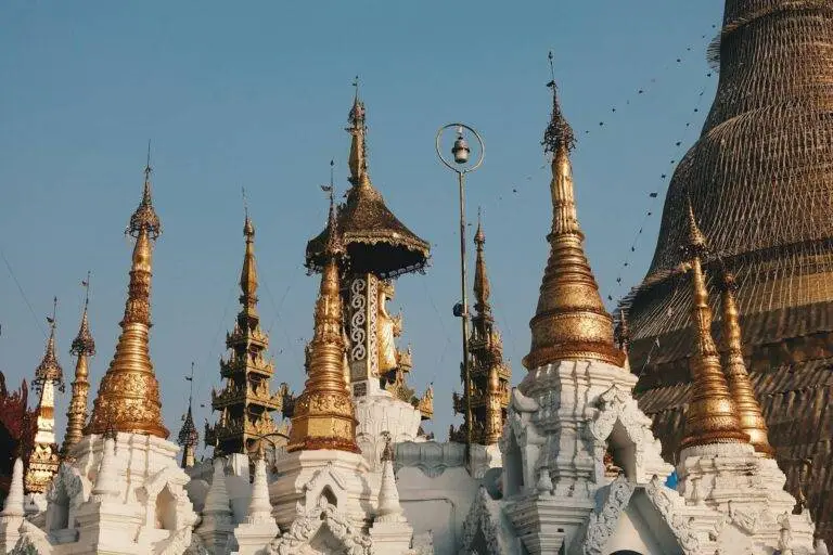 Golden spires of Shwedagon Pagoda against a clear blue sky in Yangon, Myanmar.